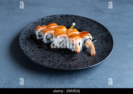 Sushi Restaurant, Uramaki Tiger serviert auf einem runden schwarzen Teller. Stockfoto