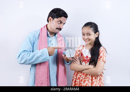 Ein indischer Landvater, der seiner Teenager-Tochter die Bedeutung von Zeit und diszipliniertem Leben erklärt. Stockfoto