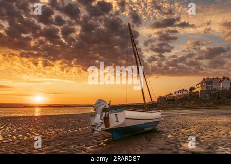 Bei Sonnenaufgang Ende Juni geht die Sonne über den Horizont, während die Flut in Richtung eines der kleinen Boote schleicht, die die Flussmündung des Flusses Torridge bei Appledore säumen Stockfoto