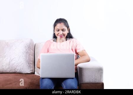 Glückliche indische Familie von Vater, Mutter, Sohn und Tochter, die mit dem Laptop surfen und eine angenehme Zeit zusammen verbringen. Die Familie schaut sich das Notebook an. Stockfoto