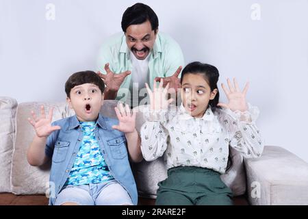 Glückliche indische Familie von Vater, Sohn und Tochter, die mit dem Laptop surfen und eine schöne Zeit zusammen verbringen. Die Familie schaut sich das Notebook an. Stockfoto