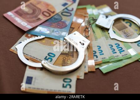 Handschellen vor dem Hintergrund von israelischem Geld. Die neuen israelischen Geldscheine (Banknoten) in Höhe von 50, 100 und 200 Schekel. Polizei-Handschellen. Finanzkriminalität Stockfoto