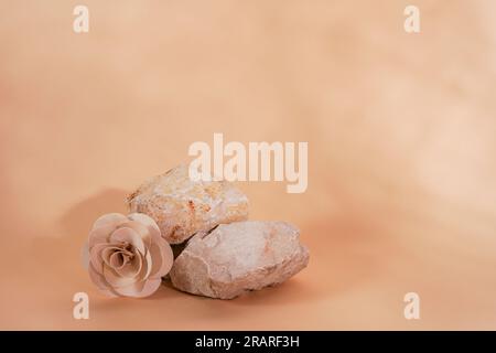 Leerer Steinstapel auf beigefarbenem Hintergrund mit Blüten und Schatten. Minimale leere Präsentationsszene für das Display-Produkt Stockfoto