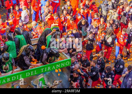 Ivrea, Italien - 19. Februar 2023: Gruppen in traditionellen Dressings und Menschenmenge mit roten Hüten nehmen an der Schlacht der Orangen Teil, Teil des Historors Stockfoto