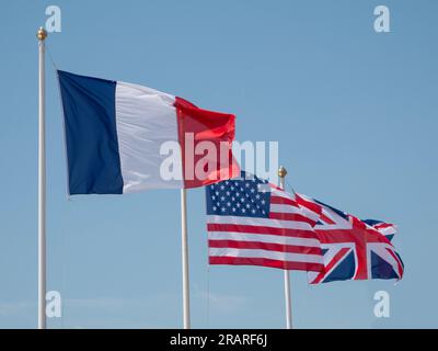 Die Flaggen Frankreichs, der USA und der Europäischen Union (EU), die im Wind auf Flaggen mit blauem Himmelshintergrund winken. Stockfoto
