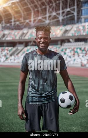 Ein junger Mann steht in einem Stadion mit einem Fußball in der Hand Stockfoto