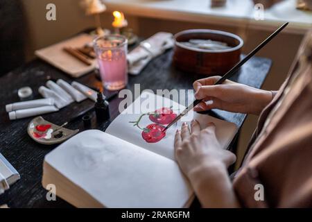 Nahaufnahme des Handzeichens im Notizbuch mit Acrylfarben. Freiberufler zieht Ordnung im Studio. Stockfoto