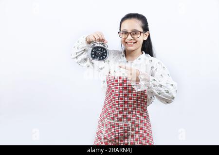 Junge Teenagerin, die einen Wecker in der Hand hält und auf den Wecker zeigt. Stockfoto