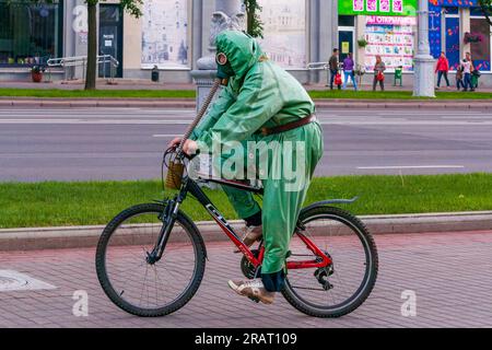 Minsk, Belarus - 15. Juni 2014: Ein Mann in einem chemischen Schutzanzug und einer Gasmaske fährt Fahrrad Stockfoto