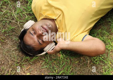 Der Fettsack lag auf dem Boden und hörte der Musik friedlich zu. Ruhige und ruhige Atmosphäre. Mit seinen Kopfhörern. Melodische Musik in die Ohren. Stockfoto