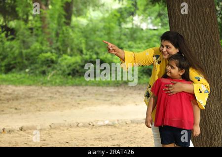 Glückliche Mutter und Tochter genießen ihre gemeinsame Zeit in einem öffentlichen Park. Alleinerziehende Mutter spielt mit ihrer Tochter in grüner und sauberer Atmosphäre. Stockfoto