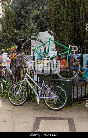 Ein Mangel an Fahrradständen hat dazu geführt, dass ein Fahrrad an Geländern über einem anderen Fahrrad, dem Market Square, Cambridge, Großbritannien, eingeschlossen wurde. Stockfoto