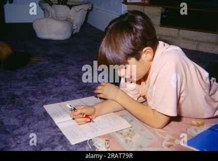 Acht Jahre alter Junge, der auf dem Boden liegt und England studiert Stockfoto