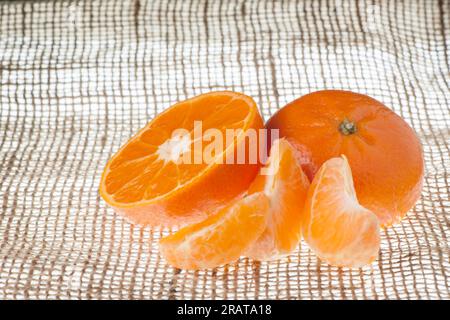 Stilleben einer halbierten Mandarine mit einzelnen Säulen auf einem Sacktuch davor. Stockfoto