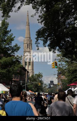 Brooklyn, NY - 18. Juni 2023: Teilnehmer gehen während der 7. Heaven Fair in Park Slope mit Kirchendetails die geschlossene Straße entlang. Es wurden viele Leute gefunden. Stockfoto