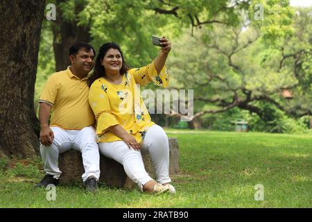 Glückliches fasto-Indianer-Paar, das Selfie in üppiger grüner Atmosphäre macht. Ruhige und ruhige Umgebung. Stockfoto