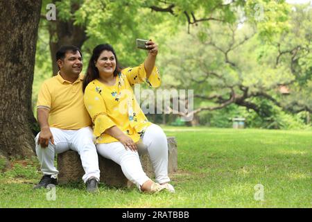 Glückliches fasto-Indianer-Paar, das Selfie in üppiger grüner Atmosphäre macht. Ruhige und ruhige Umgebung. Stockfoto