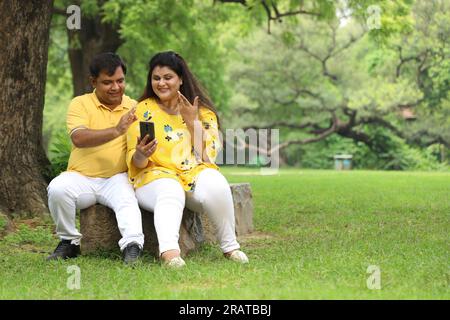 Glückliches fasto-Indianer-Paar, das Selfie in üppiger grüner Atmosphäre macht. Ruhige und ruhige Umgebung. Stockfoto