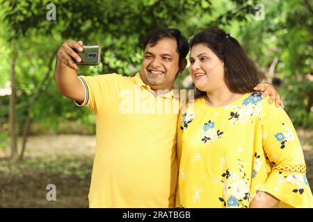 Glückliches fasto-Indianer-Paar, das Selfie in üppiger grüner Atmosphäre macht. Ruhige und ruhige Umgebung. Stockfoto