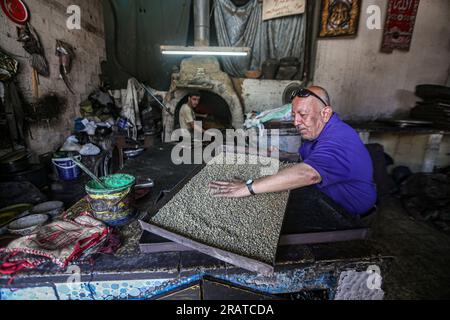 Na'im Sharab, ein 70-jähriger Palästinenser, besitzt den ältesten primitiven Ofen, der vor 130 Jahren von seinen Vorfahren geerbt wurde. Er, seine Kinder und Enkel arbeiten im Ofen der Stadt Gaza. Sharab sagt, dass sie jeden Morgen daran arbeiten, den Ofen vorzubereiten, der mit Holz und verbranntem Öl betrieben wird, das in Geschäften gekauft wurde, die Öle für Autos ersetzen. Mit der Strom- und Gaskrise haben sich einige Menschen daran gewöhnt, Brot, Kaffee und Töpfe in den Ofen zu schicken, wo der größte Anteil an Kochtöpfen während Eid al-Adha hergestellt wird, da Fleisch in großen Mengen verfügbar ist. Palästina. Stockfoto