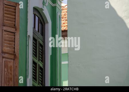 Ein Teleobjektiv mit einer grünen Wand und Fensterläden aus Bahama in einer Seitenstraße in Georgetown, Penang. Stockfoto