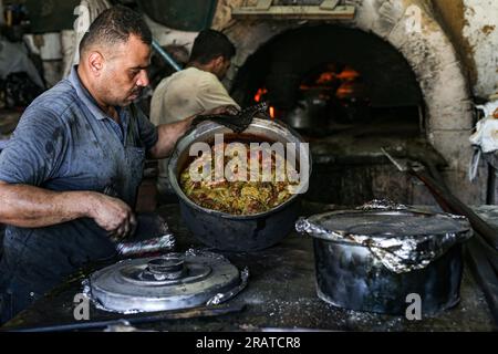 Na'im Sharab, ein 70-jähriger Palästinenser, besitzt den ältesten primitiven Ofen, der vor 130 Jahren von seinen Vorfahren geerbt wurde. Er, seine Kinder und Enkel arbeiten im Ofen der Stadt Gaza. Sharab sagt, dass sie jeden Morgen daran arbeiten, den Ofen vorzubereiten, der mit Holz und verbranntem Öl betrieben wird, das in Geschäften gekauft wurde, die Öle für Autos ersetzen. Mit der Strom- und Gaskrise haben sich einige Menschen daran gewöhnt, Brot, Kaffee und Töpfe in den Ofen zu schicken, wo der größte Anteil an Kochtöpfen während Eid al-Adha hergestellt wird, da Fleisch in großen Mengen verfügbar ist. Palästina. Stockfoto