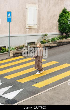 Modefrau, die den roadm überquert und eine lange Strickjacke trägt Stockfoto