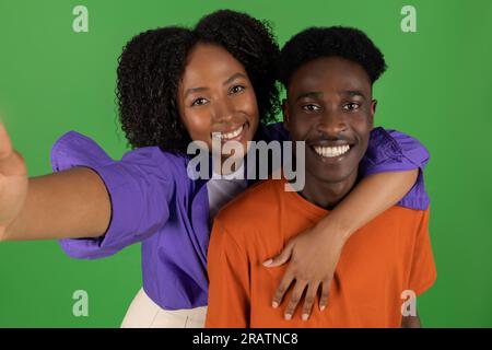 Glückliche junge afroamerikanische Frau umarmt Mann, hat Spaß, macht Selfie, genießt Freizeit Stockfoto