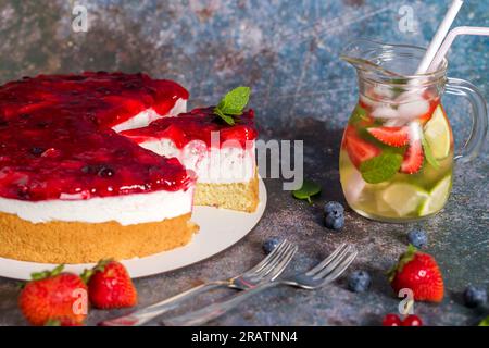 Käsekuchen mit frischen Erdbeeren, roten Johannisbeeren und Blaubeeren. Erfrischender Erdbeeren-Zitronen-Sommercocktail hausgemachter Käsekuchen Stockfoto