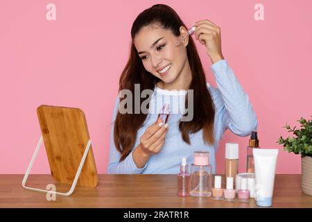 Hübsche junge braune latina, die Gesichtsöl aufträgt Stockfoto
