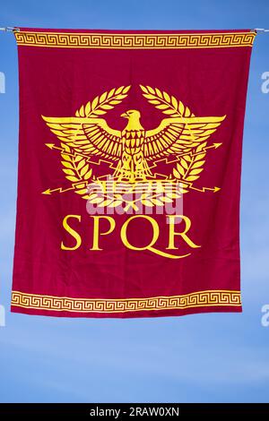 Rotes Banner in vertikaler Ansicht mit einem Symbol aus dem antiken rom, geformt von einem Adler und einem Lorbeerkranz und der Legende SPQR. Senatus Populus que Romanus Stockfoto