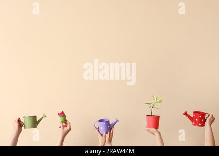 Menschen mit Gießdosen und Pflanzen auf beigefarbenem Hintergrund Stockfoto