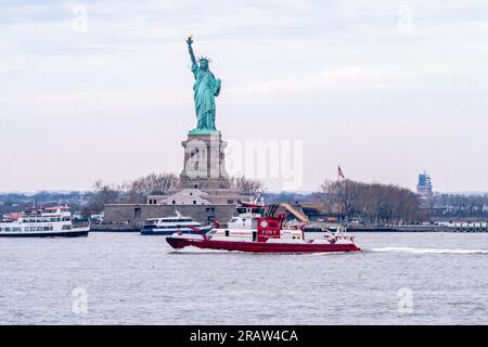 FDNY Feuerwehrboot vor der Freiheitsstatue im Hafen von New York Stockfoto