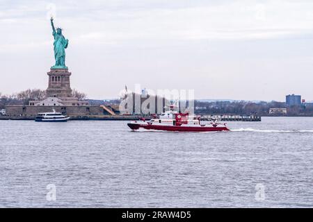 FDNY Feuerwehrboot vor der Freiheitsstatue im Hafen von New York Stockfoto