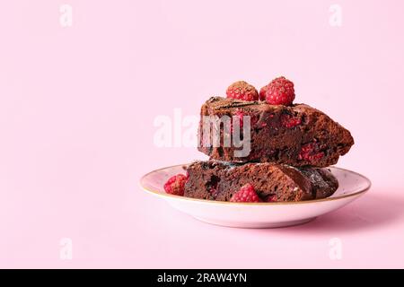 Teller mit Himbeer-Schokoladen-Brownie auf pinkfarbenem Hintergrund Stockfoto