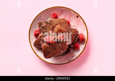 Teller mit Himbeer-Schokoladen-Brownie auf pinkfarbenem Hintergrund Stockfoto