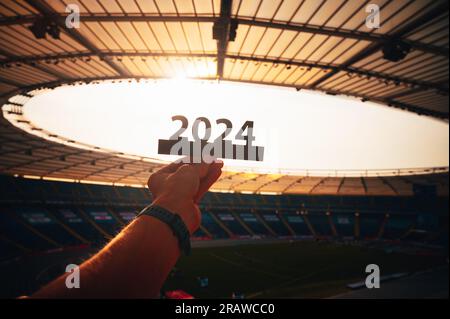 2024-jähriger Athlet im modernen Stadion. Ein Blick in die Zukunft: Silhouette des „2024“-Zeichens, das das Sportjahr und die Sommerspiele in Paris symbolisiert Stockfoto