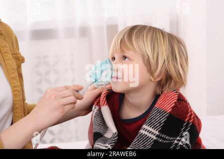 Mutter hilft ihrem kranken Sohn bei der Inhalation von Verneblern zu Hause Stockfoto