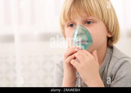 Kranker kleiner Junge mit Vernebler zur Inhalation in Innenräumen Stockfoto