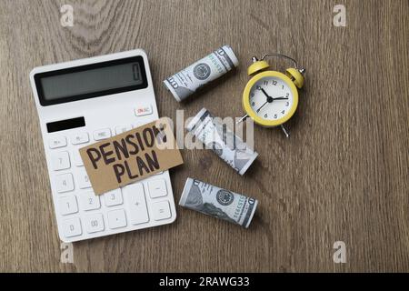 Karte mit Wörtern Pensionsplan, Banknoten, Taschenrechner und Wecker auf Holztisch, flach liegend Stockfoto
