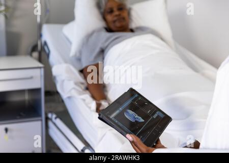 afroamerikanische Ärztin und ältere Patientin im Bett, die Tabletten im Krankenhaus einsetzt. Krankenhaus, Kommunikation, Medizin und Gesundheitsdienst Stockfoto