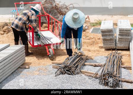 Bauarbeiter entladen Stahlstangen von einem Wagen auf der Baustelle. Stockfoto