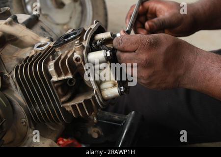 Der Mechaniker repariert ein Motorrad. Ein Mann arbeitet als Mechaniker in einer Motorradwerkstatt vor Ort. Odisha, Indien. Stockfoto