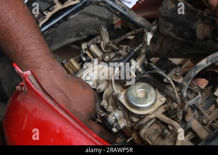 Der Mechaniker repariert ein Motorrad. Ein Mann arbeitet als Mechaniker in einer Motorradwerkstatt vor Ort. Odisha, Indien. Stockfoto