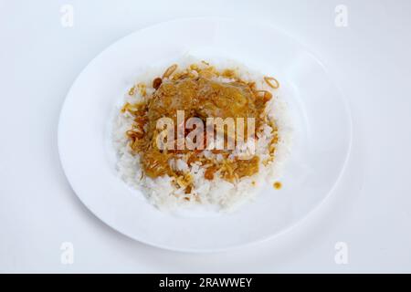 Blick von oben auf einen Teller mit warmem weißem Reis, garniert mit Hühnercurry. Padang-Reis mit Hühnchen-Curry. Stockfoto