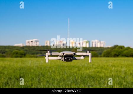 DJI Mini 2 Drohne im Flug mit Feldern und Häusern im Hintergrund: Russland - Juni 2021 Stockfoto