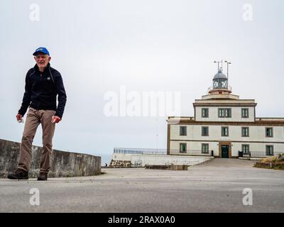 Ein alter Pilger verlässt den Leuchtturm. Der Camino de Santiago (der Weg von St. James) ist ein großes Netz alter Pilgerrouten, die sich durch ganz Europa erstrecken und am Grab von St. James (Santiago auf Spanisch) in Santiago de Compostela, Spanien. Finisterre war sowohl das Ende der bekannten Welt, bis Kolumbus die Dinge veränderte, als auch das Endziel vieler Pilger, die in den vergangenen Jahrhunderten die Reise nach Santiago machten. Pilger der vergangenen Jahrhunderte gingen auch weiter nördlich entlang der Küste zum Santuario de Nuestra Señora de la Barca in Muxía, 29km km nördlich des „Endes der Welt“ Stockfoto