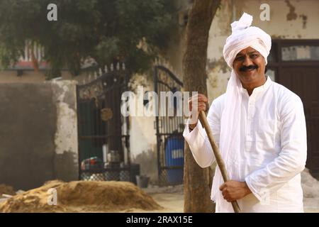 Ein Mann mittleren Alters in ländlicher Umgebung trägt einen Kurta-Pyjama, ein traditionelles Kleid für Männer in Nordindien, mit einem Gehstock. Stockfoto