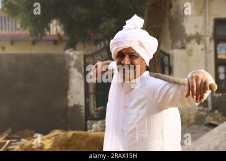 Ein Mann mittleren Alters in ländlicher Umgebung trägt einen Kurta-Pyjama, ein traditionelles Kleid für Männer in Nordindien, mit einem Gehstock. Stockfoto