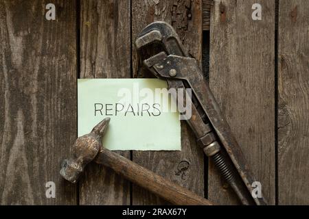 Gasschraubenhammer und neben einem Blatt mit dem Text in englischer Sprache reparieren auf einem Holztisch reparieren Stockfoto